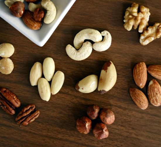 Close-up of various nuts on a wooden table, showcasing healthy snacking options.